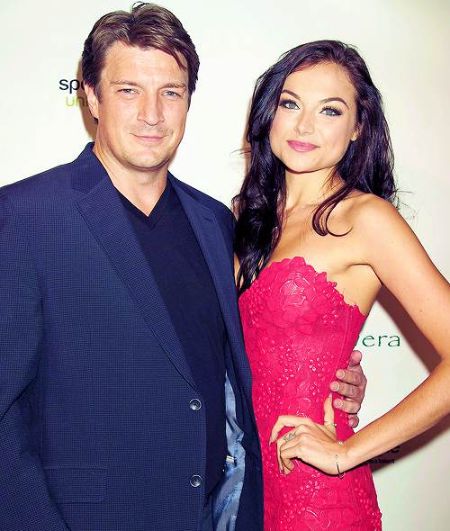 Nathan Fillion in a blue suit poses with Spanish Christina Ochoa.